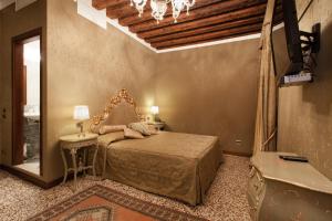 威尼斯阿尔蓬特默西尼果酒店的一间卧室配有一张床、一张桌子和一面镜子