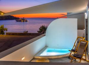金尼昂Oro Suites的阳台上设有浴缸,享有水景