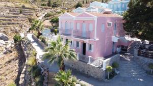 锡米Niriides Hotel Apartments的享有棕榈树粉红色房子的空中景致
