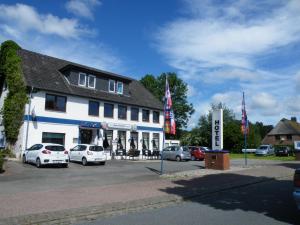 JagelLandgasthof "Hotel zum Norden"的一座白色的大建筑,汽车停在停车场
