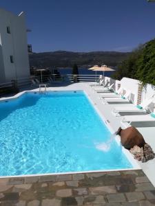 萨摩斯天蝎座公寓酒店及套房的一座大型游泳池,旁边设有白色椅子