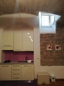 阿西西Appartamento Sant'Apollinare的厨房配有白色橱柜和砖墙