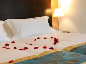 阿旺什SWISS HOTEL LA COURONNE的一张床上有红色玫瑰花瓣的床