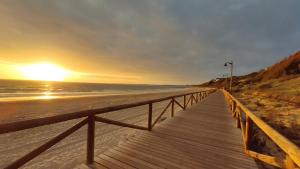圣玛丽亚港Apartamentos Bahía Blanca的一条木板路,在日落时分通往海滩