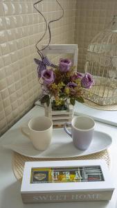 斯雷姆斯卡米特罗维察Angellina Apartmani的一张桌子,上面有两个杯子,一个盘子上有紫玫瑰