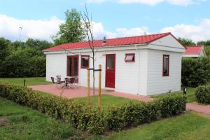 DrijberHofgalow Chalet op camping "De Stal"的一间白色的小小屋,设有红色屋顶