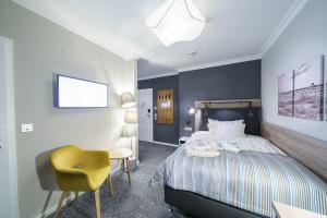 库克斯港都恩斯塔兰德酒店的一间卧室配有一张床和一张黄色椅子