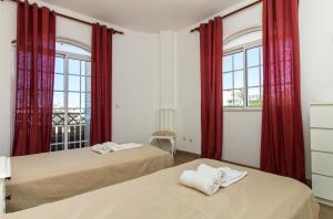 阿尔布费拉Albuera Villa的配有红色窗帘的客房内的两张床
