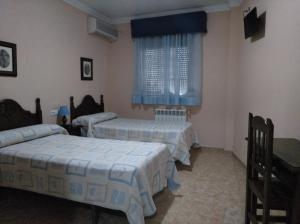 卢塞纳多边形旅馆的客房设有两张床和一扇带蓝色窗帘的窗户。