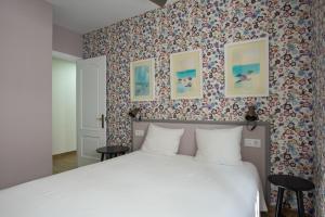 科尼尔-德拉弗龙特拉Piso Conil的卧室配有白色的床和花卉壁纸