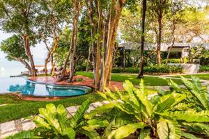 南芭堤雅The Monttra Pattaya - SHA Extra Plus的一个带游泳池和树木的花园