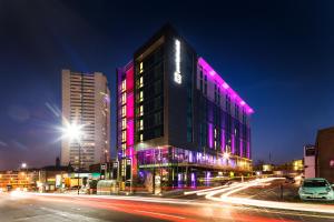 伯明翰pentahotel Birmingham的城市街道上一座紫色灯的建筑