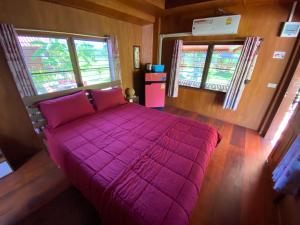 三百岭Jing Jo Boutique Bungalow的一间卧室设有一张大紫色床和两个窗户
