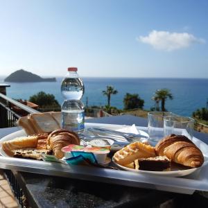 阿拉西奥Verde Mare的包括面包和糕点的托盘以及一瓶水