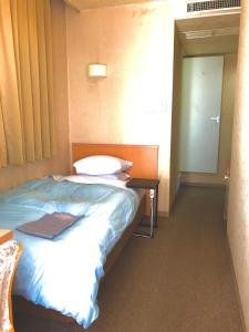 高冈市朝日市客栈酒店的一间卧室配有一张床和一张带镜子的桌子