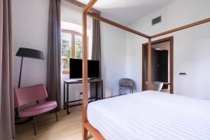 苏特里Antico Borgo di Sutri的一间卧室配有一张床、一张书桌和一台电视