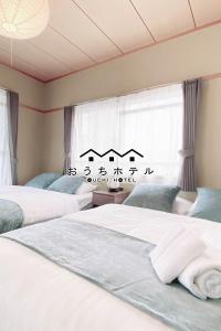 广岛OUCHI HOTEL Itsukaichi的带窗户的客房内的两张床