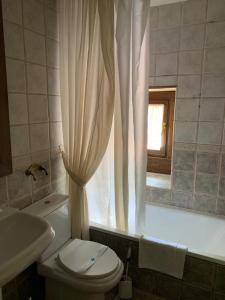 哈卡查理酒店的一间带卫生间的浴室和一个带窗户的浴缸