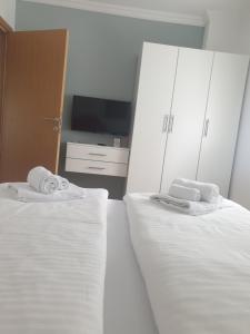 维尔蒂尼克Apartmani Kruna的一间卧室配有两张带白色床单的床和电视。