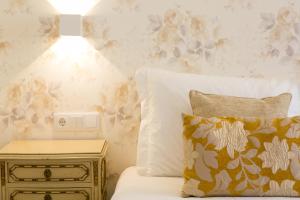 里斯本Suites Amália Guesthouse near Rossio Square的一间卧室配有一张床和一个带台灯的边桌