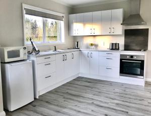 坎布里奇Maungatautari Outlook Cambridge的白色的厨房配有白色的橱柜和微波炉