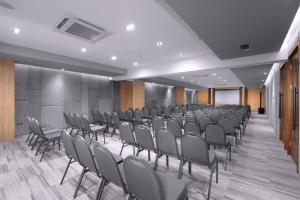 雅加达Neo Hotel Puri Indah的一间会议室,里面摆放着一排椅子和讲台