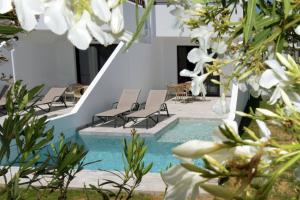 普拉塔尼亚斯Geraniotis Hotel and Resort的一个带椅子的游泳池,鲜花白色