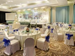 雅加达安佐尔会议中心美居酒店的宴会厅配有白色的桌子和白色的椅子