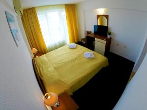 希典罗拓思酒店的一间小卧室,配有黄色的床和镜子