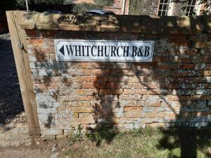 阿德敏斯特Whitchurch Farm Guesthouse的砖墙上的白色街道标志