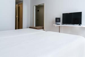 卡索拉Sercotel Ciudad de Cazorla的卧室配有白色的床和平面电视。