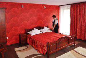 AktenburgPensiunea Filonul de Aur的站在一个房间红色床边的人