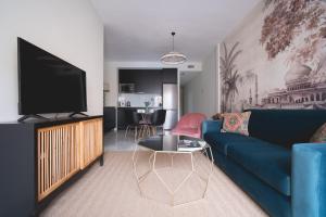 塞维利亚Arco Macarena Suite的客厅配有蓝色的沙发和电视