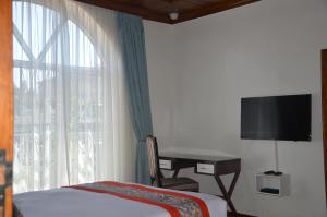 基加利Villa Asimba的一间卧室配有一张床、一张书桌和一个窗户。