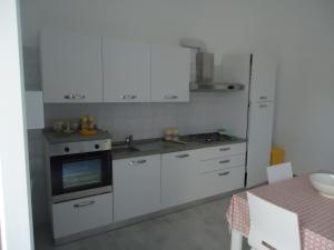 莱乌卡Appartamento Leuca的厨房配有白色橱柜、炉灶和冰箱。