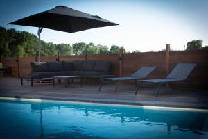 弗尔内B&B Presende的一个带沙发和遮阳伞的庭院,毗邻一个游泳池