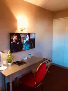 圣康坦索勒Hôtel Le Gue Du Holme的客房设有书桌和墙上的电视