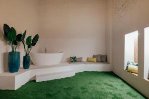 塞维利亚Hotel Cetina Sevilla的浴室设有白色浴缸和绿色地毯。