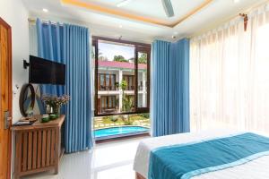 富国Caesar Phu Quoc Hotel的一间带蓝色窗帘和床的卧室以及游泳池