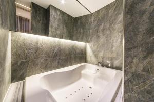 仁川市Guwol Hotel的浴室铺有灰色瓷砖,配有白色浴缸。