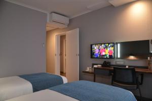 德班Town Lodge Umhlanga的酒店客房设有两张床、一张桌子和一台电视。
