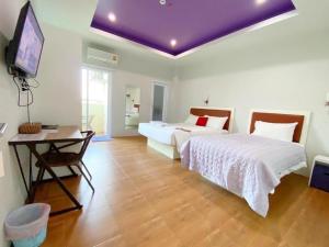 董里南丕酒店的一间卧室设有两张床和一个紫色的天花板