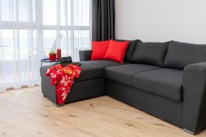 普里莫尔斯科Aparthotel Primorsko的客厅里配有带红色枕头的灰色沙发