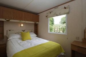 萨默顿The Nest - Family friendly caravan nr Glastonbury & Street的一间卧室配有一张带黄色枕头的床和窗户