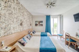 里摩日Contact Hôtel Limoges - HOTEL DES DEUX MOULINS的酒店客房配有两张床和一张书桌