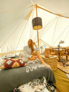 GaulverjabærCamp Boutique的坐在帐篷里的床上的女人