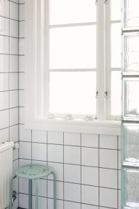 TingstädeMejeriet Stenkyrka的白色瓷砖浴室设有凳子和窗户
