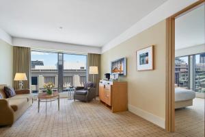 悉尼The Fullerton Hotel Sydney的一间客厅,客厅配有沙发和一张书桌,位于酒店的房间
