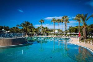 圣伊西多罗萨兰托村蓝色酒店的一座棕榈树和遮阳伞的大型游泳池