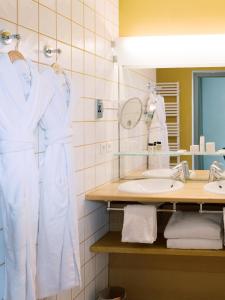 圣雷米普罗旺斯影响酒店的浴室设有白色浴袍和水槽